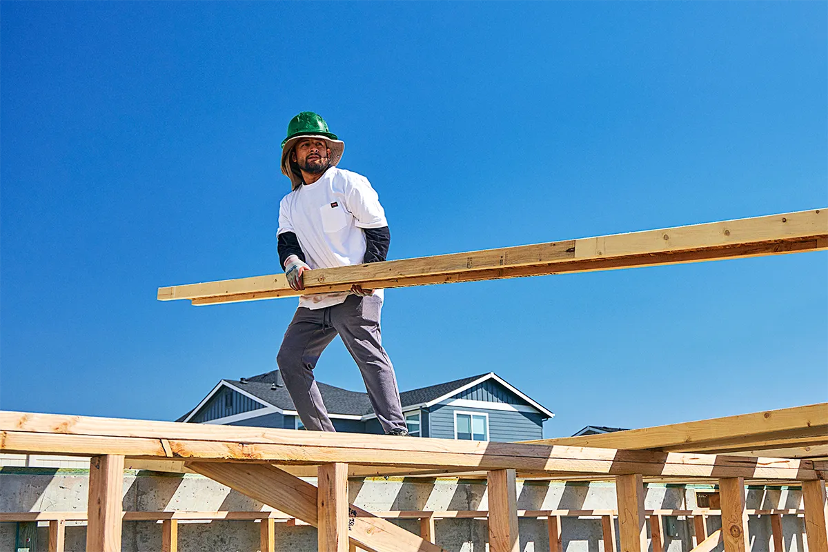Man working on a job site lifting up a length of I-Joist