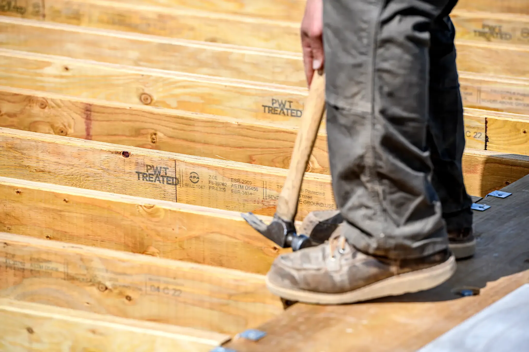 Person with hammer standing on a frame built with PWT Treated LVL