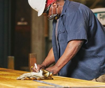 A worker in a hard hat writing measurements on a board